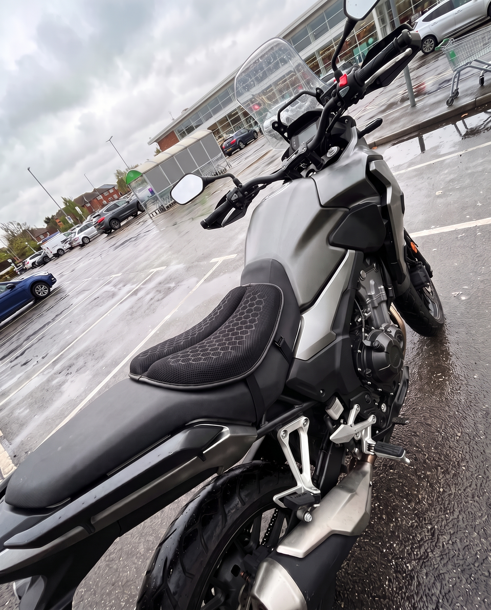 MotoCush gel seat pad on the rider seat of an adventure bike in a wet car park