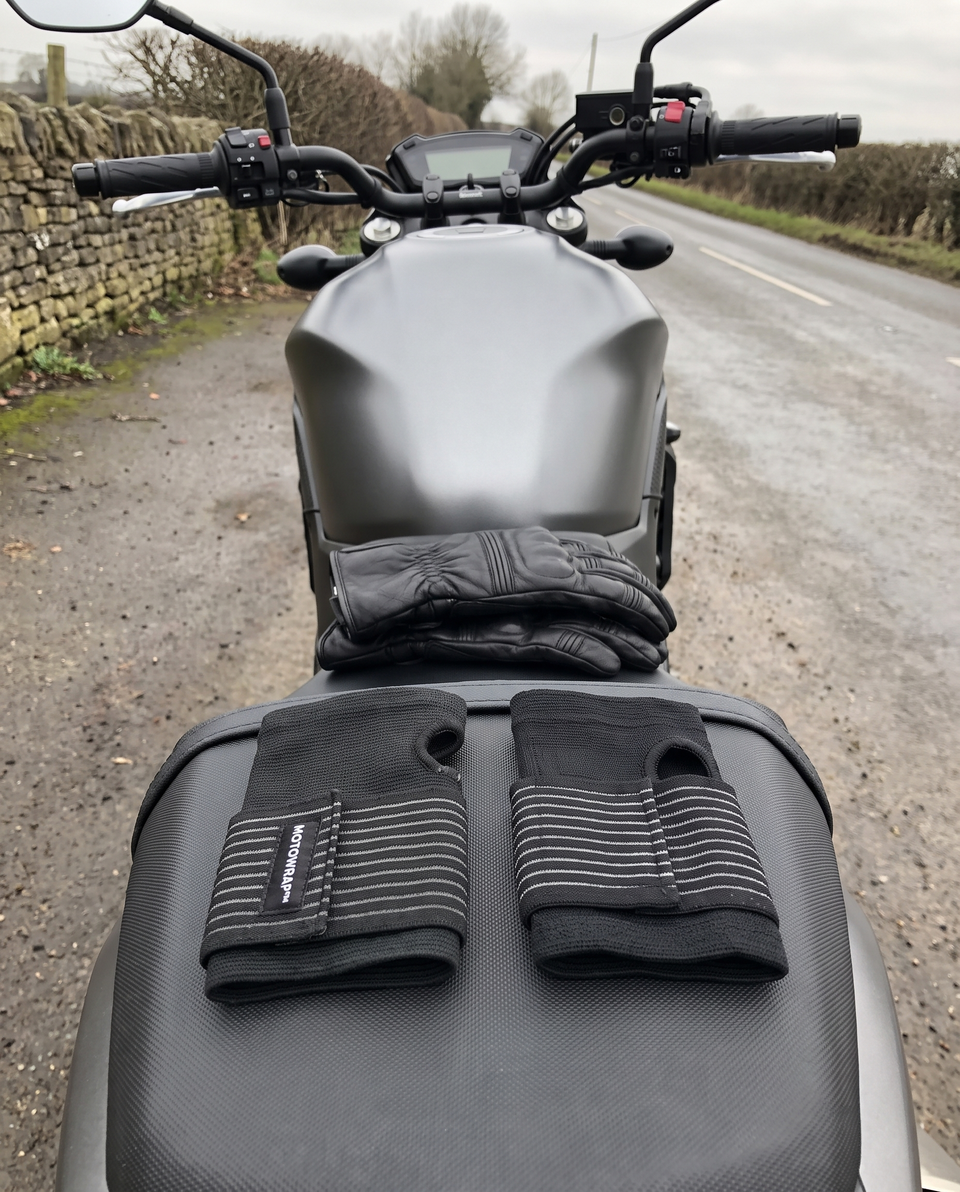 A pair of MotoWrap wrist supports on a motorcycle seat with riding gloves